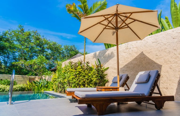 Umbrella and chair around swimming pool neary beautiful landscape of sea ocean beach with blue sky and white cloud for leisure travel and vacation